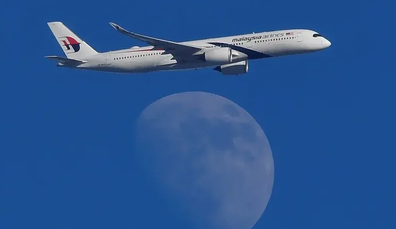 A Malaysian Airlines Airbus A350-900 passenger aircraft is seen flying in front of the moon, over London, Britain. (Reuters)